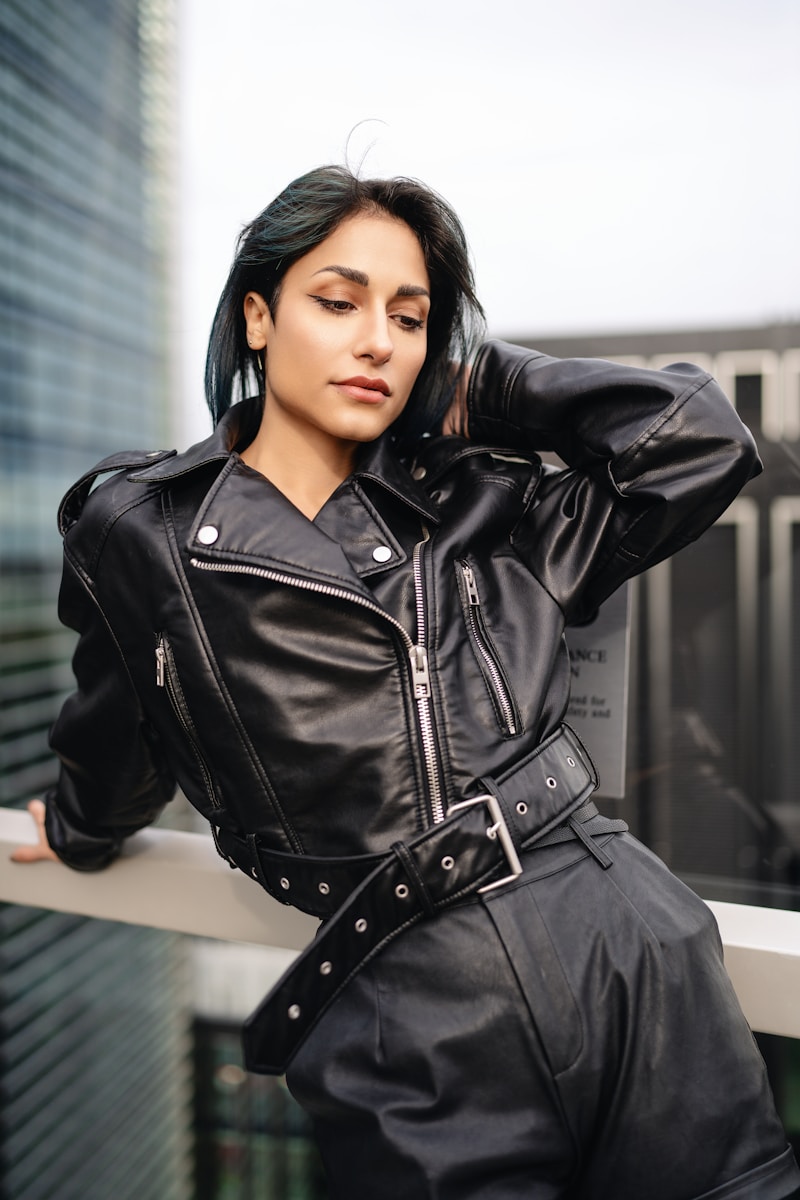 A woman in a black leather outfit leaning on a ledge